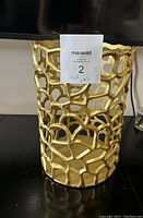 Full front view of large gold openwork metal decorative vase with label showing lot number and name