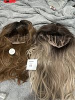 Two synthetic hair wigs placed side by side showing interior cap construction and hair color blending.