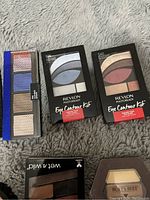 Photo showing three Revlon Photoready Eye Contour Kits sealed in packaging plus Burt's Bees and Wet n Wild makeup items.