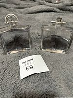 Two clear glass bottles of Givenchy Pi Neo men's cologne on a grey fabric background, one with visible chips and both with sprays.