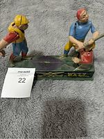 Full front view of the vintage 1950s cast iron baseball mechanical coin bank with three players and the word BASEBALL on the base.