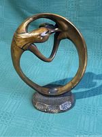 Oblique front view of abstract bronze-toned sculpture displaying the circular embracing couple.