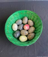 Green basket holding all 11 polished marble eggs with various colors and patterns