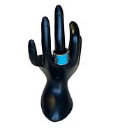 Ring displayed on a black hand-shaped ring holder showing the front and size positioning.