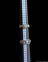 Two vintage women's rings on a ring sizing stick, showing sizes between 7 and 9.5.