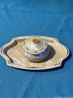 Lot of two pieces: frosted jar with lid and decorative scalloped tray beneath, both cream colored with blue accents.