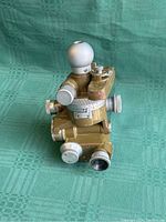 Front and top view of the vintage KMZ artillery aiming circle, showing spherical knob, adjustment dials and optical lens on olive drab metal body.