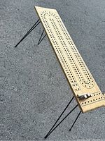 Side angle showing the cribbage board with track holes and metal legs unfolded.