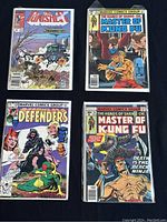 Photo showing four vintage Marvel comic books including The Punisher, The Defenders, and two Master of Kung Fu issues