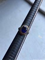 Front view of men's vintage silver ring with large oval blue stone on sizing stick showing size 10.