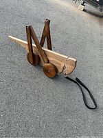 Front and side angled view of the handmade wooden grasshopper pull toy showing the carved head, wooden wheels, and articulated legs connected with dowels.