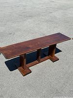 Front view of dark wooden bench showing rectangular seat and three vertical supports on base.