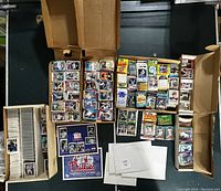 Three cardboard boxes filled with baseball cards, a Phillies promotional poster, and a Yankees poster visible.