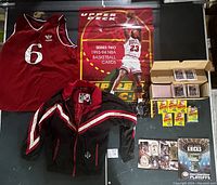 Full lot view showing 76ers jersey, Bulls jacket, trading cards, sealed Fleer packs, Upper Deck poster