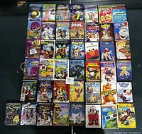 Photo showing an array of 47 children's DVD cases laid out in rows on a black surface. Cover titles include The Nightmare Before Christmas, Barney, Madagascar, Shrek, and Garfield among others.