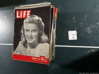 Stack of vintage Life magazines with black and white cover featuring a woman, dated November 12, 1945.