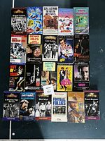 Photo of 23 assorted VHS tapes laid out on a surface showing titles and cover art