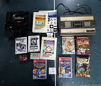 All items in the lot arranged on floor: SEGA Genesis console, Mattel Intellivision console, SEGA games, multiple PC games, software application booklets, and game cartridges.