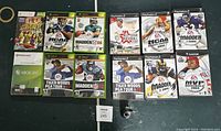 Photo showing Xbox 360, Xbox Original, and PlayStation 2 sports video games including Madden NFL, Tiger Woods PGA Tour, NCAA Football, All Star Baseball.