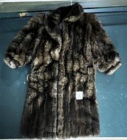 Full view of vintage brown fur coat laid flat showing its texture, collar, length, and cut details.