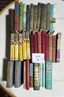 Top-down photo showing approximately 35 vintage books arranged in rows on a table. Titles including Cherry Ames and Nancy Drew are visible. Shows condition and variety of books.