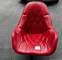 Front view of the vintage red tufted lounge chair showing tufted diamond-pattern upholstery and curved armrests.