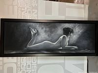 Full view of the large framed black and white oil painting showing the reclining nude woman.