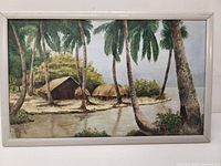 Full view of the framed tropical scene painting showing palm trees, huts, water, and foliage with artist signature.