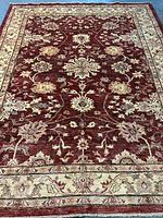 Full view of rug laid flat showing red field and beige border