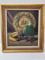 Full view of the framed oil painting showing the still life with fruit and decorative plate.