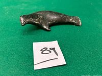 Full side view of the stone carving on a green background with a lot number card