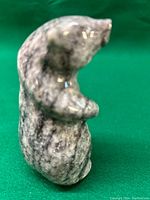 Side view of polished stone bear carving showing texture and standing posture.