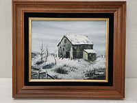 Framed winter barn oil painting with snowy landscape and green barn.