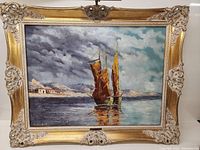 Front view of the framed oil on board painting showing sailboats on water, cloudy sky, and mountains in the distance, with ornate gold frame.