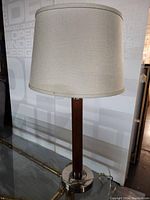 Full view of Mid-Century Modern style table lamp showing white fabric drum shade, wooden cylindrical body, and metallic base.