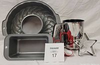 Photo displaying the full lot: 9 inch Bundt pan, mini loaf pan, stainless steel sifter, and two cookie cutters (heart and star).