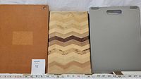 Three cutting boards: a brown composite board, a handmade wooden chevron board, and a gray composite Martha Stewart board with handle.