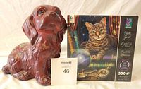 Photo showing a brown ceramic dog figurine and a Ceaco 550-piece puzzle box titled "Night Spirit" with a tabby cat illustration.