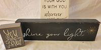 Black square sign reading 'You are Loved' and long black rectangular sign reading 'shine your light' with starburst design