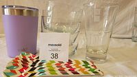 Photo showing lavender travel mug, colorful dessert spoons, clear glass bowls, and the Nespresso coffee glass all arranged together with lot card in center.