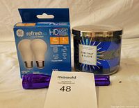Lot contents: Bath & Body Works Chestnut & Clove 3-wick candle, purple mini Maglite flashlight, GE Refresh LED 40W equivalent lightbulbs in original box.