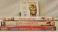 Three DVDs stacked horizontally with spines visible and book titled 'Cat Psalms' standing behind them, showing front cover featuring a kitten.