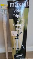 Photo showing Maxell video tripod and camera bag in original box, with a white photo shoot umbrella in packaging next to it.