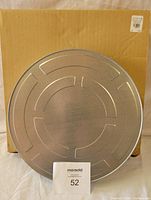 Top view of the large circular metal film reel can with embossed design, placed on a cardboard box background.