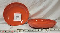 Two reddish-orange West Elm soup or salad bowls displayed against a white background with measuring tape indicating size (approx. 7 inches in diameter).
