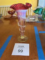 Full view of the antique Vaseline bud vase showing the tall slender body, ruffled red rim, and clear ruched glass spiral trim wrapping around the vase body.