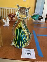 Front side of the glass cat figurine showing yellow stripes on blue background with clear glass head and tail.