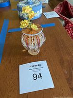 Full view of the Heron art glass bud vase displaying its shape and pattern with artificial yellow flowers shown inside.