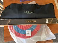 View of all items: black carry case with L.L.Bean logo, boxed arrows, and circular rope target laid out on table.