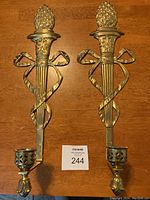 Pair of brass wall sconces with pineapple motif and candle holders